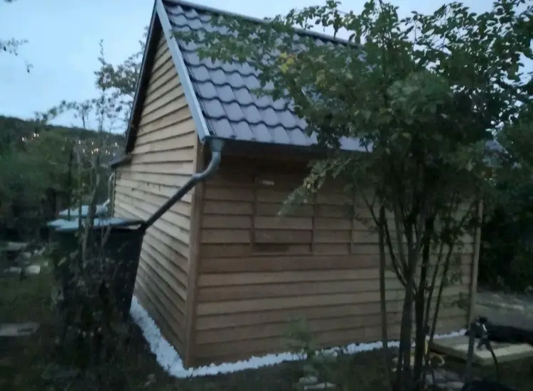 Ein kleiner Holzschuppen mit Dach.