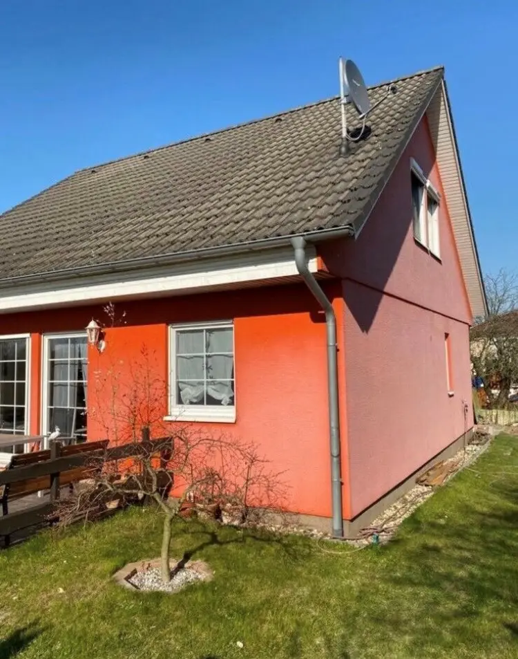 Ein Haus mit einer orangefarbenen Fassade und einer Terrasse.