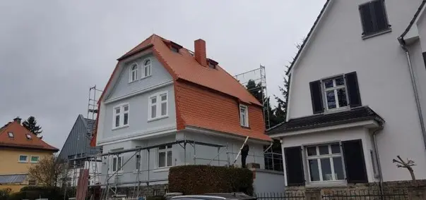 Ein Haus mit orangefarbenem Dach und einem davor geparkten Auto.