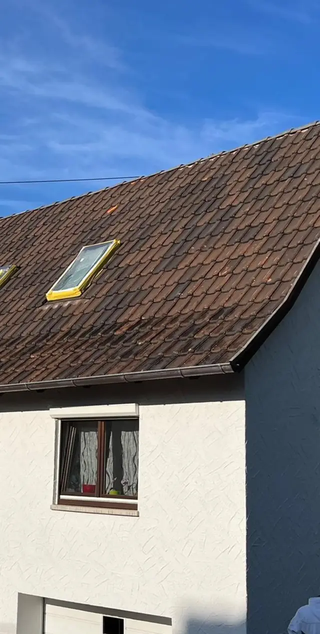 Satteldach mit verwitterten braunen Dachsteinen vor der Beschichtung.