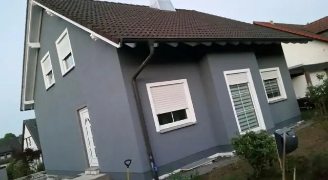 Ein Haus mit grauer Fassade und weißen Fensterläden.