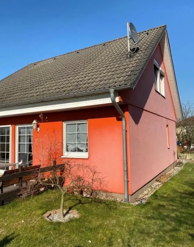 Ein Haus mit einer orangefarbenen Fassade und einer Terrasse.