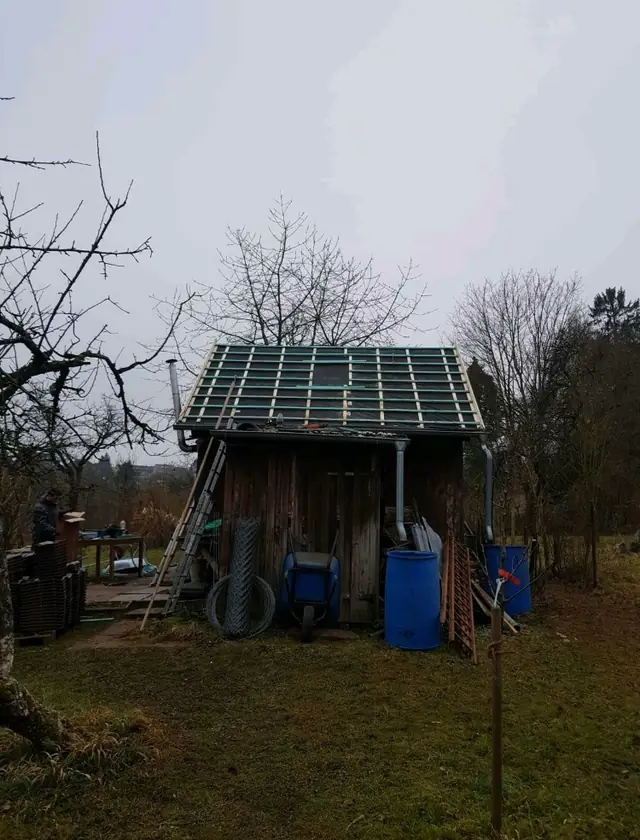 Ein kleiner Schuppen mit einem Dach aus Metall.