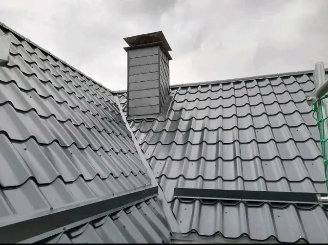 Ein Metalldach mit Kamin und Dachrinnen.