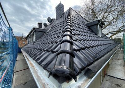 Das Dach eines Hauses mit schwarzem Ziegeldach.