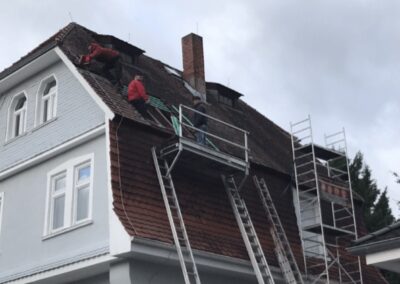 Ein Mann arbeitet am Dach eines Hauses.